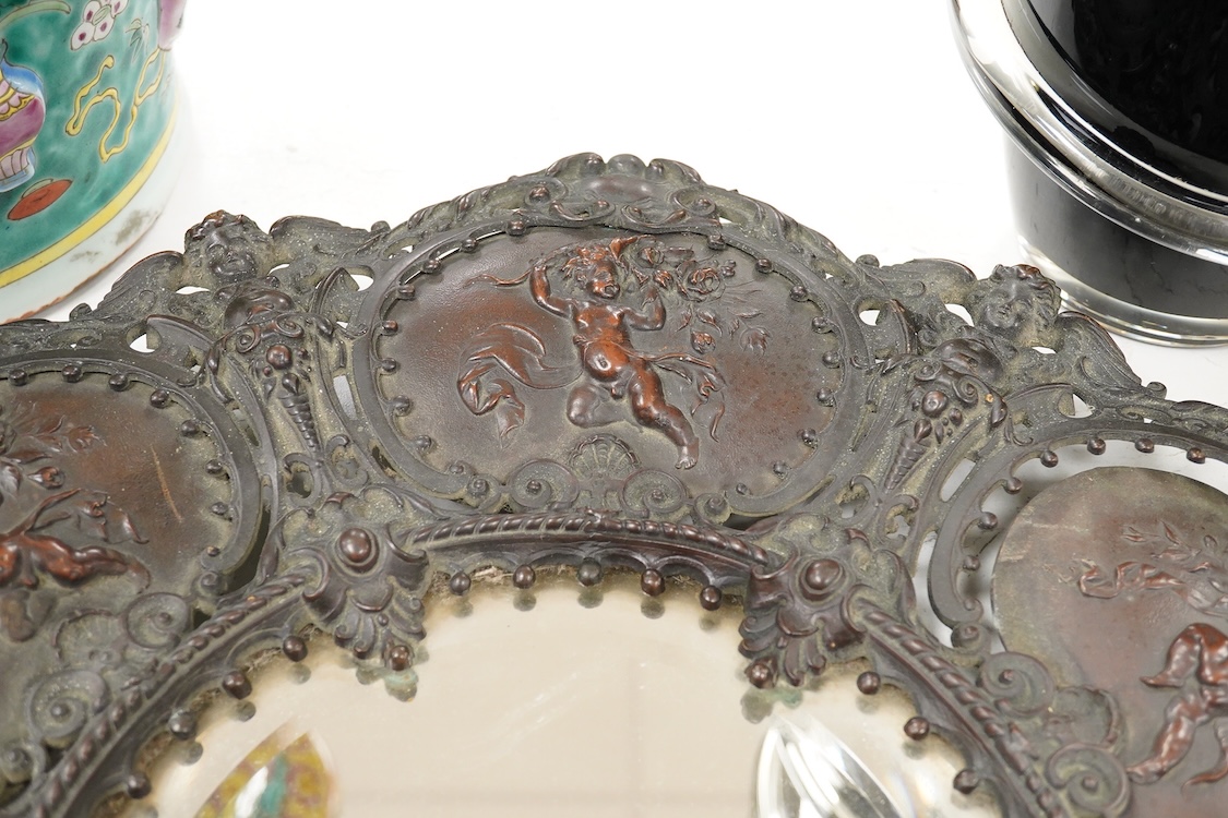 An ornate circular decorative bronzed metal putti decorated wall mirror, 40cm